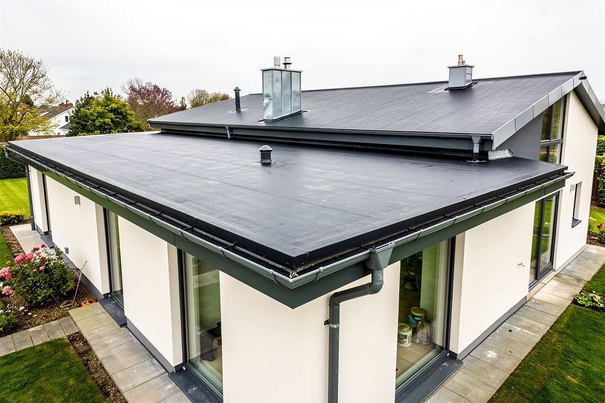 Huopakaton ja bitumikaton korjaus Jämijärvellä tuo kestävyyttä ja suojaa variables[width=1200,height=800,description=Photorealistic photo of a new bitumen roof of detached house, picture taken from medium distance (showing some surroundings), not too deltailed, no text, no logos]