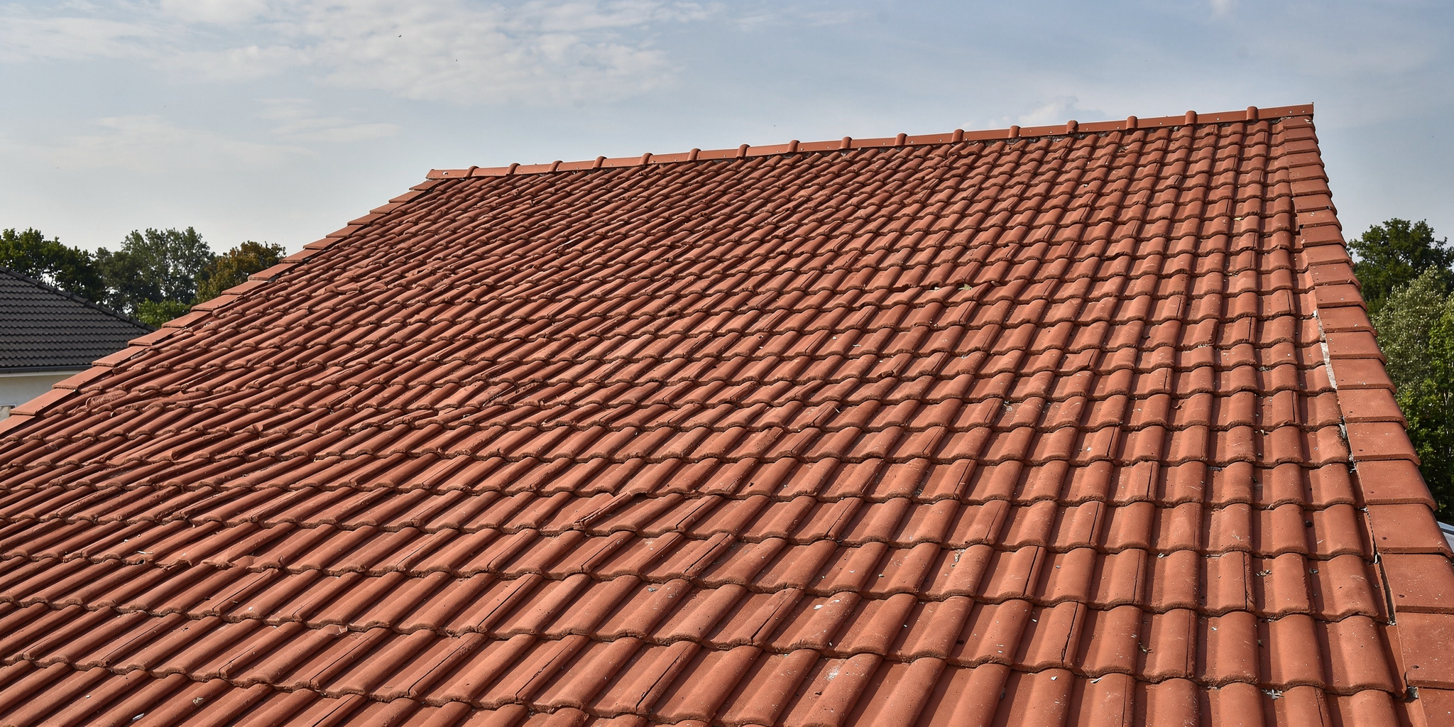 Katon korjaus variables[width=2048,height=1024,description=Photorealistic image from medium distance (showing some surroundings) of good condition tile roof OR metal sheet roof (choose one). Not too detailed. Natural daylight. No people, no text, no logos]